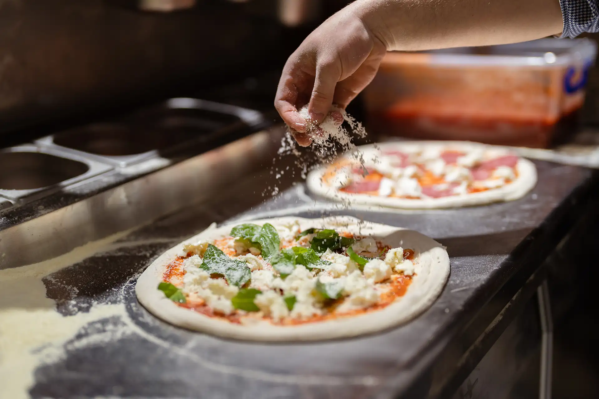 Pizza wird mit Käse belegt